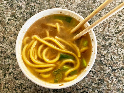A takeout container of ya-ka-mein noodle soup in New Orleans